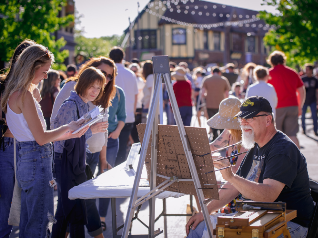 Attendees of the 2022 ART 64 event watch as a competitor paints.